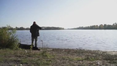 Sakallı balıkçı nehir kıyısında balık tutuyor. Nehri üzerinde bir olta ile Balık tutma dostum. Nehir Balık tutma. Ağır çekim.