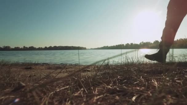 太陽の下で歩く男性の足付近の川. — ストック動画