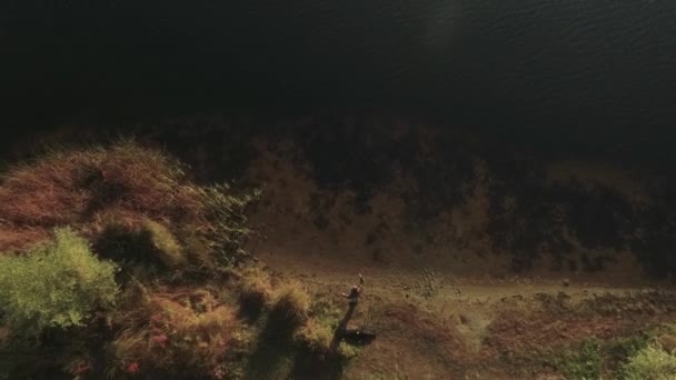 Una vista dall'alto del pescatore con una canna da pesca sulla riva del fiume. Sparatoria dal drone . — Video Stock