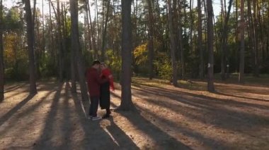 Yukarıdan bir kaç kucaklayan bir çam ormanı günbatımı ışık görüntüleyin. Sevgi dolu bir ırklararası çift bir tarih ve hugs var. Dron--dan ateş. Ağır çekim.