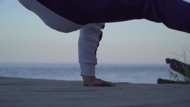 A man in casual wear dancing breakdance on the background of a lake. Man dancing in free style outdoors. Slow motion. — Stock Video