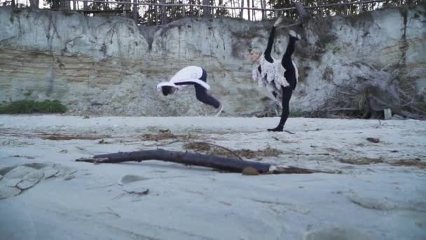 Deportes joven pareja interracial bailando contemporáneo al aire libre. Chico asiático y chica caucásica bailando en estilo libre. Adolescentes en ropa casual bailando en la orilla arenosa del río. Movimiento lento . — Vídeo de stock