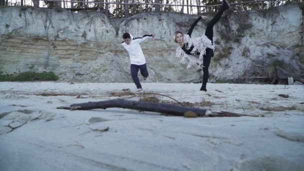 Casual joven pareja interracial bailando contemporáneo al aire libre. Chico asiático y chica caucásica bailando en estilo libre. Adolescentes en ropa casual bailando en la orilla arenosa del río. Movimiento lento . — Vídeo de stock