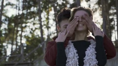 Mutlu Interracial çift boş zaman güneş ışığı bir arka plan üzerine açık havada geçirir. Neşeli beyaz kız ve erkek arkadaşı gülümseyen bir randevum var. Güneş kısa sarı saçlı güzel bir kız öpücük.