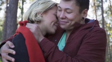 Kaç çam ağaçları ve gün batımı hafif bir arka plan üzerinde öpüşme aşk içinde gülümseyen genç. Mutlu aile açık havada vakit.