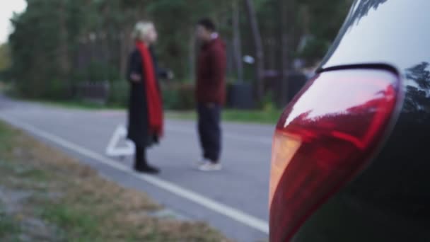 Twee mensen zweren op de achtergrond van een gevarendriehoek. Silhouet van het paar te vloeken. Focus op auto aanmelden. — Stockvideo