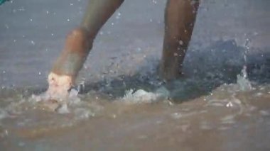 Deniz suyu ve kıyı üzerinde çalışan kadın ayakları. Bacaklar splash plajda yapma kız.
