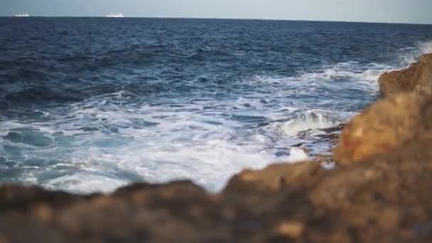 Marés colidem contra as pedras formando espuma de mar branco. A água é limpa e pura — Vídeo de Stock