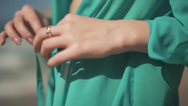 Woman hands untie the laces on turquoise cape and expose the belly close up. Dress fluttering in the wind — Stock Video