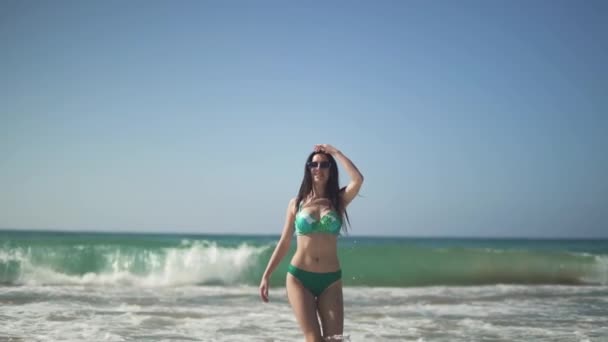 Bella donna con un corpo perfetto che indossa bikini e cammina sulla spiaggia . — Video Stock