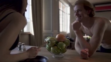 Mutlu çift sabah mutfakta kahvaltı hazırlarken gülüyor. Kadın iç çamaşırı seksi sıcak kız ve delikanlı iç çamaşırı mutfak masasının durmak ve birbirlerine gülümse.