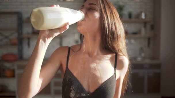 Προσωπογραφία γυναίκας με το τέλειο σώμα, εσώρουχα, πίνουν το γάλα και να χυθεί κάποια. Ευτυχισμένος κορίτσι πίνει στην κουζίνα. — Αρχείο Βίντεο