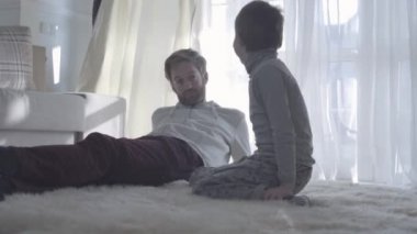 Genç çocuk ile baba görüşmeler sakallı. Sakallı baba beyaz halı ve yanındaki oğlu yalan. Baba-çocuk ilişkisi.