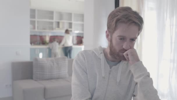 Portrait de triste homme barbu debout dans le salon gros plan. Femme et garçon sont en arrière-plan. Relations familiales. Problèmes familiaux. Mouvement lent . — Video