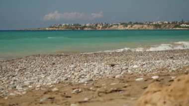 Masmavi denizin pitoresk Kıbrıs Adası'nın arka plan üzerinde boş bir taşlı plaj çökmesini köpüklü dalgaları