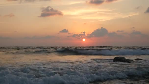 Beautiful sunset with colorful cloudy sky and extremely large waves which create huge splashes and foam — Stock Video