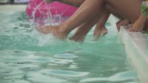 Štíhlé ženy štíhlé nohy vytvářet obrovské vody ve venkovním bazénu. Volný čas a zábava dívky.