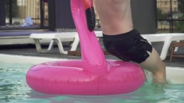 Genç komik adam eğlenceli hafta sonu ve flamingo, şişme yüzme havuzunda su sıçramalarına oluşturma atlama