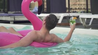 Genç komik yüz tarafından şişme flamingo sıcak esmer ve yüzme havuzunda sevimli seksi sarışın