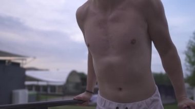 Genç sportif üstsüz adam kendini mavi akşam gökyüzü arka plan üzerine açık Bahçesi çubuğunda yukarı çeker