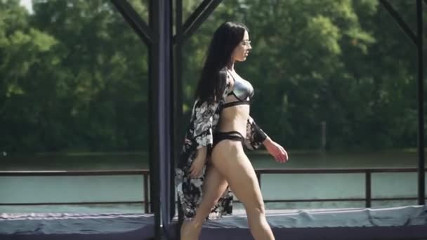 Cute Brunette Woman Silver Black Swimming Suit Walks River Bank — Stock Video