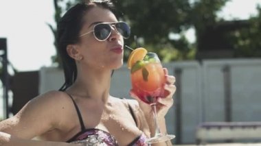 Neşeli güleryüzlü kadın onun kokteyl içme güneş gözlüğü. Bir bikini yalnız kadın eğlence.
