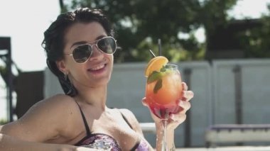 Neşeli güleryüzlü genç kadın onun kokteyl içme güneş gözlüğü. Bir bikini yalnız kadın eğlence.