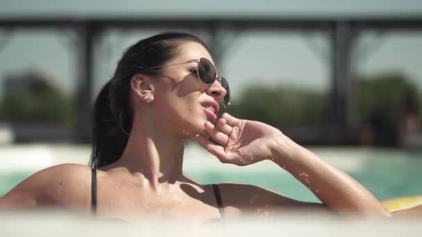 Porträtt av vuxen brunett kvinna i solglasögon simning i poolen. Fritid för ensamma damen i bikini. — Stockvideo