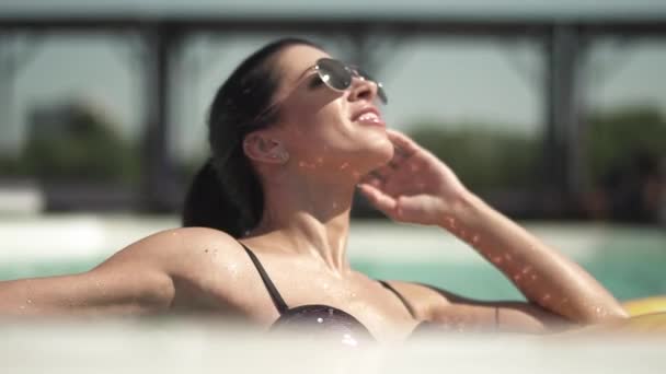 Porträt einer niedlichen Frau mit Sonnenbrille, die im Pool schwimmt. Freizeit einsamer Dame im Bikini. — Stockvideo