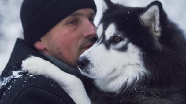 Portret mężczyzny w odzież wierzchnia zima, przytulanie i rozmawia z husky na zewnątrz. Facet z jego zwierzę. — Wideo stockowe