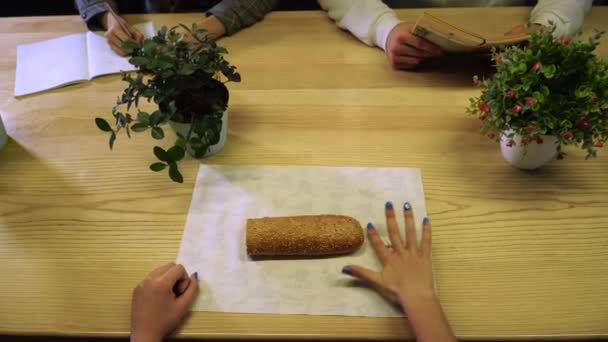 Chica quita las pastillas del papel de regalo, toma un sándwich fresco en las manos y va a morderlo — Vídeo de stock