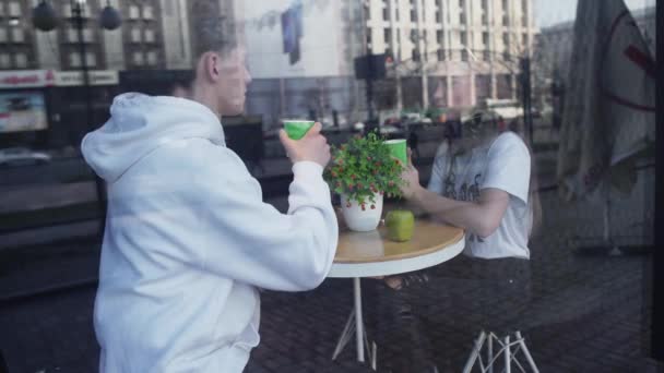 约会的女孩和男人坐在舒适的咖啡馆里喝咖啡 圆桌上躺着绿色的苹果 花瓶里站着一朵花 — 图库视频影像