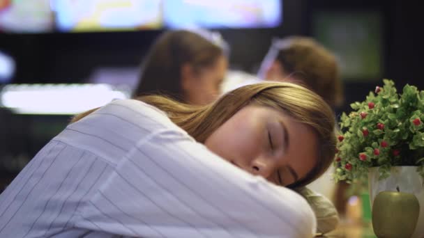 Una giovane ragazza dorme appoggiata a un tavolo in un caffè. Dormire ragazza in un bar cibo sano sullo sfondo di una giovane coppia . — Video Stock