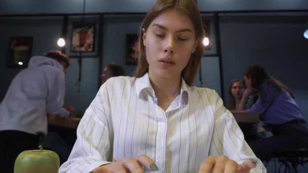 Krásná dívka v knihovně nebo v kavárně tiskne něco na počítači na pozadí komunikace mladých lidí — Stock video