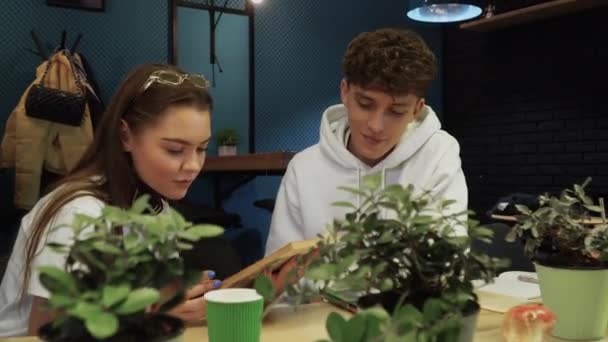 Studenti sedí v kavárně přečíst knihu a chat. Volný čas mladých lidí, zdravý životní styl. — Stock video