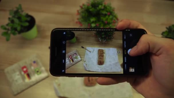Kvinnlig hand ta bilder på smartphone av färska aptitretande rulle med dekorationer på bordet. — Stockvideo