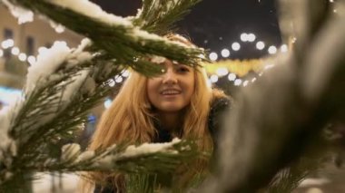 Mutlu neşeli kar Noel ağacı dalları ile kar köknar ağacı dalında yakınındaki kızsın ön planda.