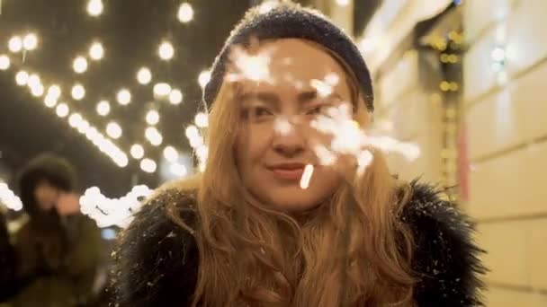 Portret van de jonge vrouw retty met wonderkaarsen in handen close-up. Sparks verstrooit in verschillende richtingen — Stockvideo