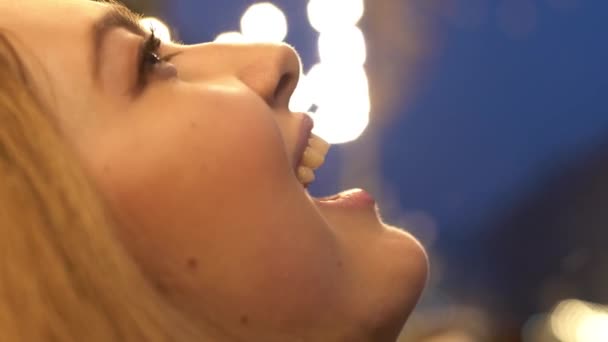 Close-up van speelse vrouwelijke gezicht sneeuwvlokken vangen met haar mond haar tong popping. Schattig meisje heeft plezier in de winter buiten — Stockvideo