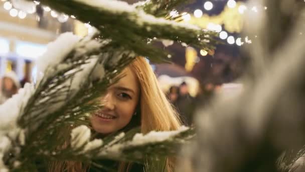 Young Woman Looking Camera Christmas Tree Branches Snow Foreground Lady — Stock Video