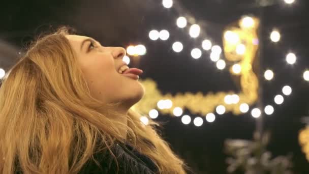 Gelukkig mooie jonge vrouw spelen outdoor, proberen te vangen van sneeuwvlokken met haar tong close-up — Stockvideo