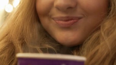 Bir kış ceket bir kış sokakta duran ve karton bardak sıcak çay onun elinde tutan uzun sarı saçlı güzel güleryüzlü genç kız portresi yakın çekim.