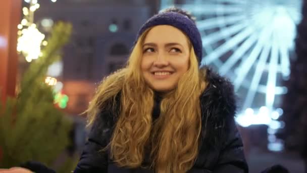 Porträtt av unga leende kvinna i vinter hatt talar tittar i kameran utomhus — Stockvideo