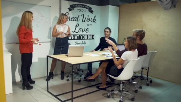 Setkání brainstormingu tým obchodníků. Dvě dívky představí úspěšné strategie v zasedací místnosti kreslení grafu na bílou tabuli visí na zdi kanceláře — Stock video