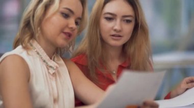Two young employeers discuss new ideas about development of their company using papers, stickers and pens