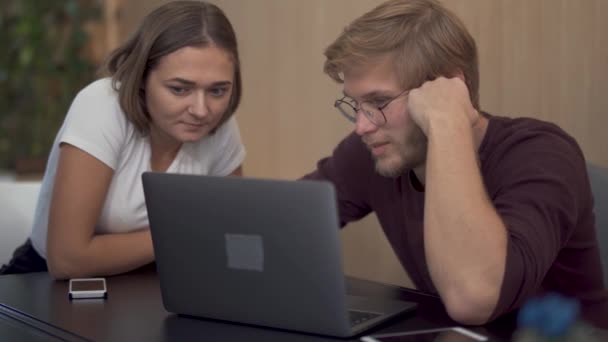 Dva kolegové se zaměřují na sledování něčeho zajímavého a užitečného na obrazovce přenosného počítače v kanceláři — Stock video