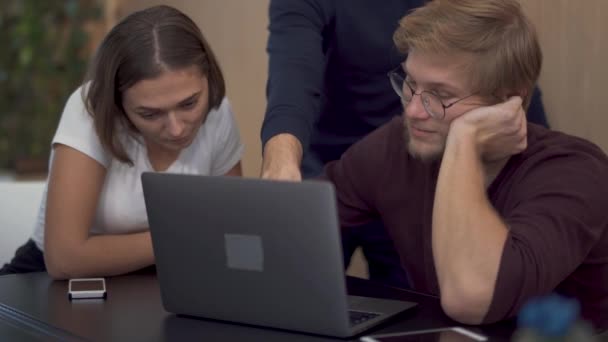 Женщина не согласна со своим коллегой, который показывает новую полезную информацию на ноутбуке в коворкинге — стоковое видео