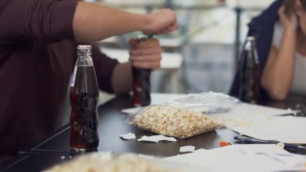 Male team member opens pepsi glass bottle with the help of cigarette lighter for his colleague on the break after hardworking — Stockvideo