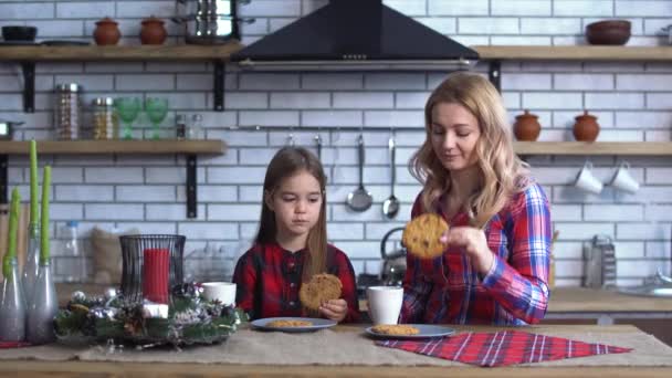 Madre e figlia si siedono sul tavolo della cucina e mangiano biscotti con caffè — Video Stock