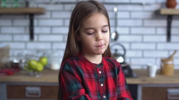 Pequena menina safada sorridente com cabelos castanhos longos brincar com cookies na cozinha — Vídeo de Stock